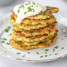 a stack of zucchini fritters with sour cream on top