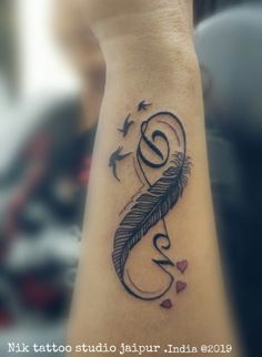 a tattoo on the wrist of a woman with birds flying around her and a feather in the shape of a letter s