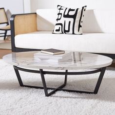 a marble coffee table sitting on top of a white rug in front of a couch