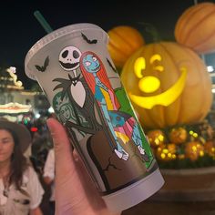 a person holding up a starbucks cup in front of pumpkins and jack - o'- lanterns