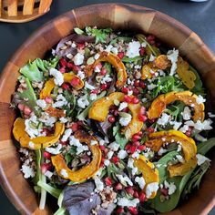 a salad in a wooden bowl on top of a table next to a fork and knife