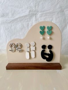 a wooden stand with earrings and earring holders on it's sides, against a white background