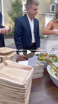 a man and woman standing in front of a table full of plates with food on it