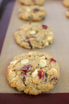 cookies with cranberries and white chocolate chips are lined up on a baking sheet