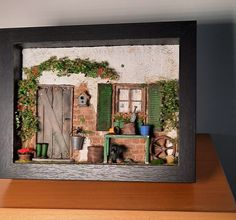 a miniature house with potted plants on the windowsill