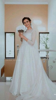 a woman in a white wedding dress holding a bouquet of flowers and posing for the camera