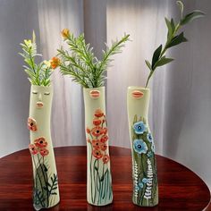 three vases with flowers in them sitting on a table