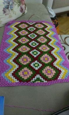 a crocheted rug is laying on the floor in front of a couch and chair