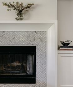 a white fireplace with a vase on top of it