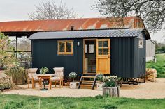 a small black shed sitting on top of a lush green field