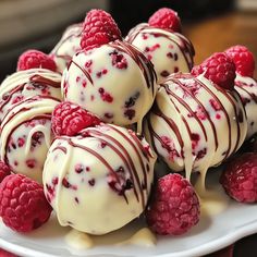 white chocolate covered raspberry truffles on a plate with fresh raspberries