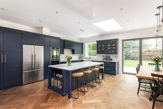 a large kitchen with blue cabinets and an island in the middle, surrounded by wooden flooring