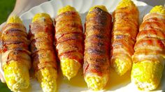 corn on the cob wrapped in bacon is being held by someone's hand