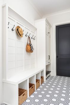 a white entryway with black doors and baskets on the wall next to it,