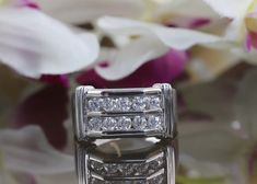 a diamond ring sitting on top of a table next to flowers and white orchids