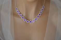 a purple and white necklace on a mannequin with veil around it's neck