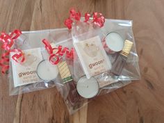 three small candles in plastic bags on a wooden table with red ribbons and bows around them