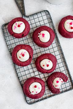 red velvet cookies with white frosting on a cooling rack