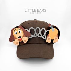 a brown hat with two dogs on it's front and the word, little ears boutique