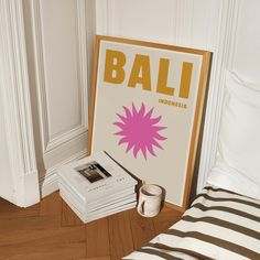 a stack of books sitting on top of a wooden floor next to a poster with the word bali