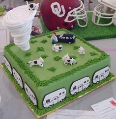 a cake that is on top of a table with some decorations in the shape of cars and football helmets