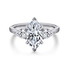 a diamond ring with three pear shaped diamonds on the band and an oval center stone