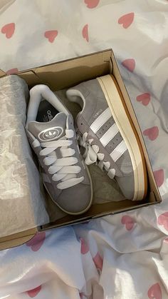 a pair of adidas sneakers in a box on a bed with pink and white hearts