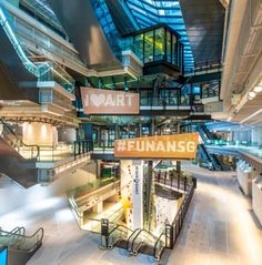 the interior of a building with stairs and signs hanging from it's ceilings