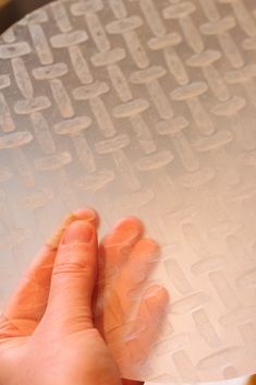 a person holding onto a piece of paper on top of a table with holes in it