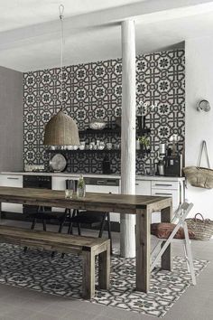 a dining room table and bench in front of a wall with black and white tiles