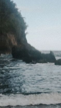 a man standing on top of a beach next to the ocean holding a surfboard