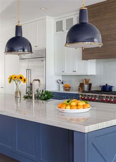 a bowl of fruit is sitting on the kitchen counter top, with two pendant lights above it