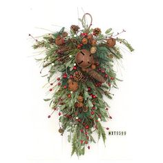 a christmas wreath with pine cones, berries and evergreens hanging on a white wall