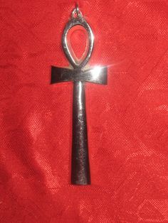 an egyptian cross pendant on a red cloth with the word love written in silver letters