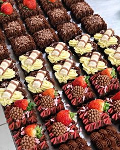 chocolates and strawberries are arranged in rows on a table with other desserts