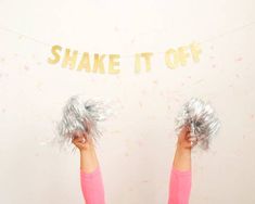 a woman is holding her hands up in front of a sign that says shake it off