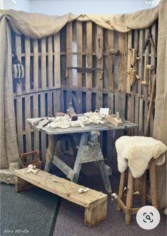 a table with two stools and a bench in front of an old wooden wall