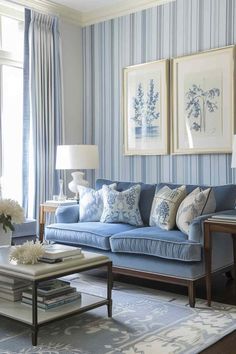 a living room with blue couches and pictures on the wall above them in front of a window