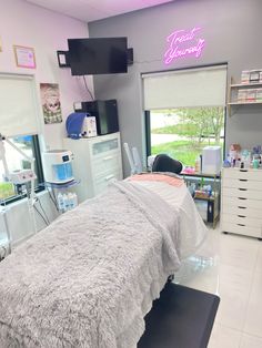 a bed in a room with lots of windows and lights on the wall above it