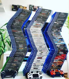 several stacks of video game cases stacked on top of each other in front of a plant