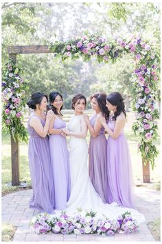 the bride and her bridesmaids pose for a photo in front of an arch decorated with flowers