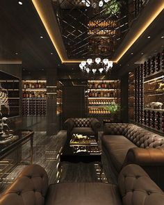 a living room filled with brown couches and lots of wine bottles on shelves above them