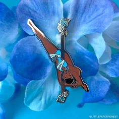 a blue flower with a pin in the shape of a woman on it's back