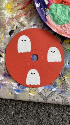 the paint is red and white with two ghost faces on it, next to a paper plate