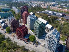 an aerial view of some buildings in a city with lots of green trees and tall buildings