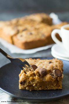 chocolate chip cookie bars on a plate with a fork and cup of coffee in the background