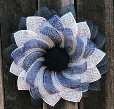 a large blue and white flower sitting on top of a wooden fence