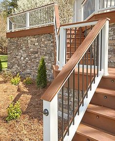 a wooden stair case next to a brick wall and stone steps in front of a house