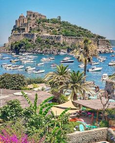 boats are in the water near an island with a castle on it's side