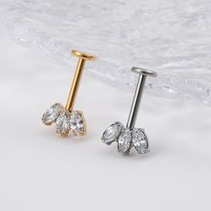 two pairs of gold and silver nose studs with clear crystal stones on each side